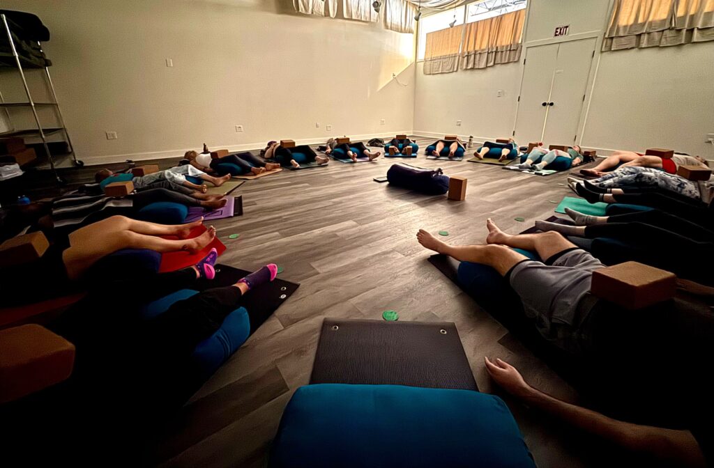 A group enjoying Savasana during a yoga class at the SYC studio.